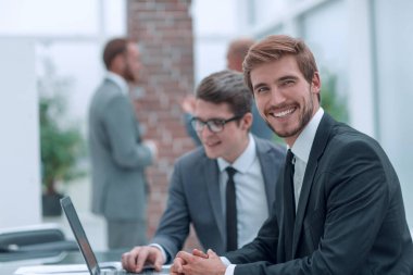 İş adamları büro masasında oturarak konuşur.
