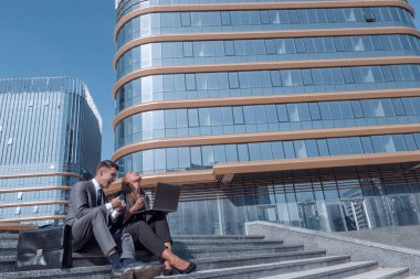 Mutlu şirket çalışanları sokakta dizüstü bilgisayar kullanıyor..