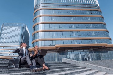 corporate employees sitting on the steps in front of the business center