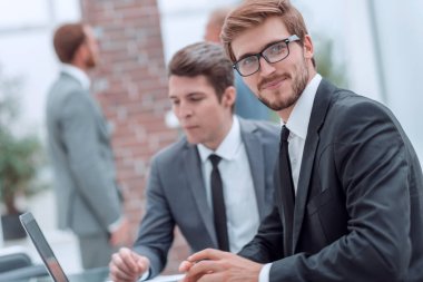 İş adamları büro masasında oturarak konuşur.