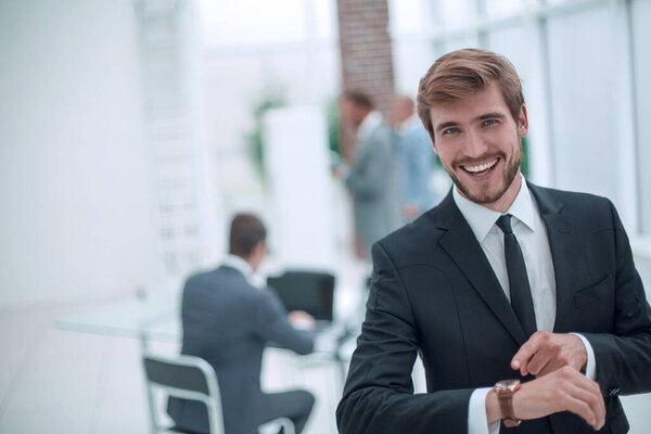 smiling businessman pointing to his wrist watch.