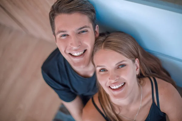 幸せな若いカップルが床に座ってカメラを見て — ストック写真