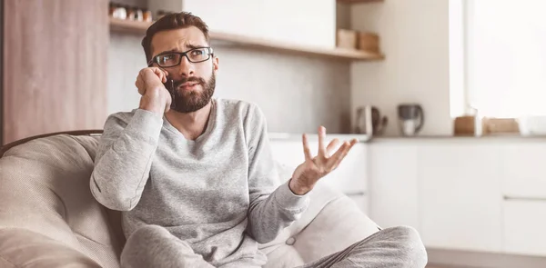 stock image cheerful man talking on a mobile phone sitting in a comfortable chair