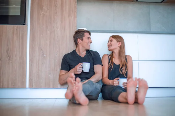 一对年轻夫妇坐在新厨房的地板上 — 图库照片