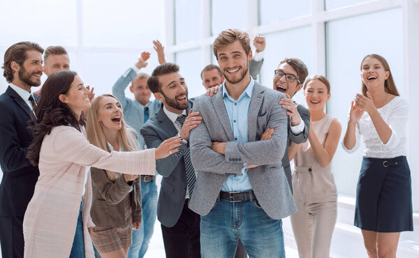 счастливый молодой бизнесмен, стоящий среди коллег
