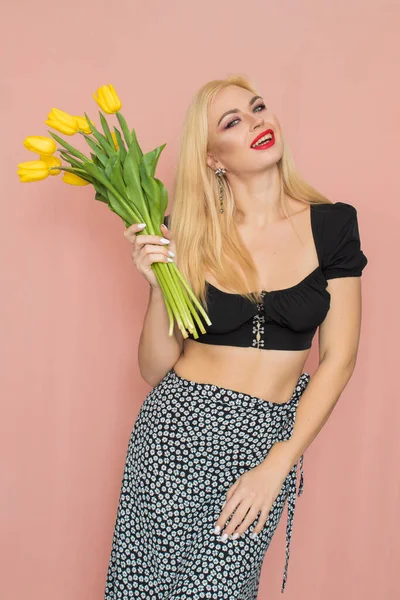 Woman in black top and skirt holding yellow tulips