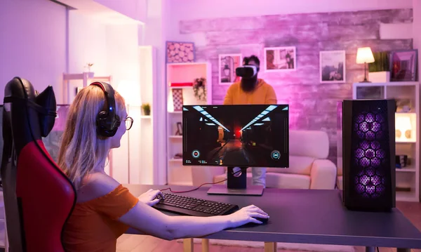ブロンド女の子座っています上のゲームチェアで部屋にカラフルなネオンライト — ストック写真