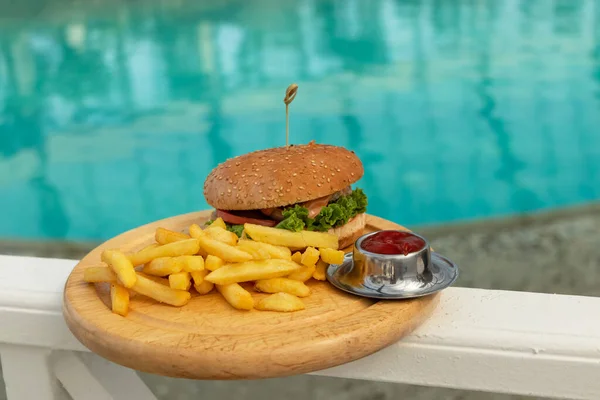 おいしいハンバーガー 食欲をそそるフライドポテトとケチャップ ビーチで明るく暑い晴れた日に海でリラックスして食事をするというコンセプト ソフトフォーカス — ストック写真