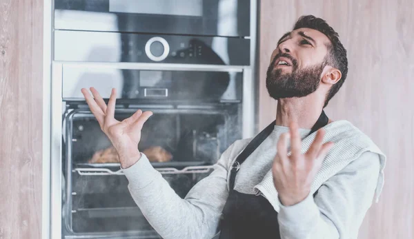 焼かれたクロワッサンと一緒にオーブンの近くに立つ驚くべき男 — ストック写真