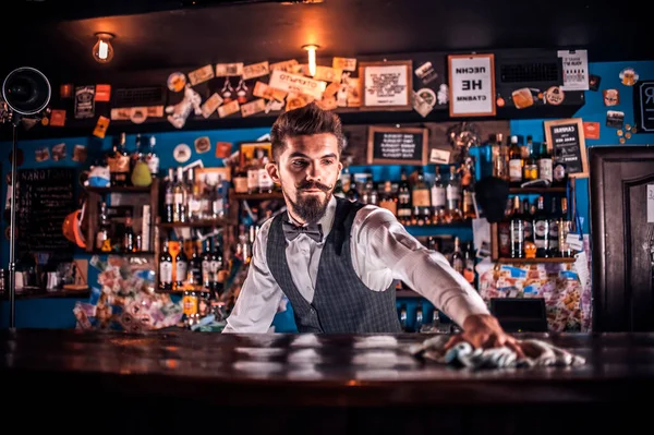 酒吧间服务员站在酒吧间柜台旁边时 酒吧间的特点是在鸡尾酒中添加配料 — 图库照片