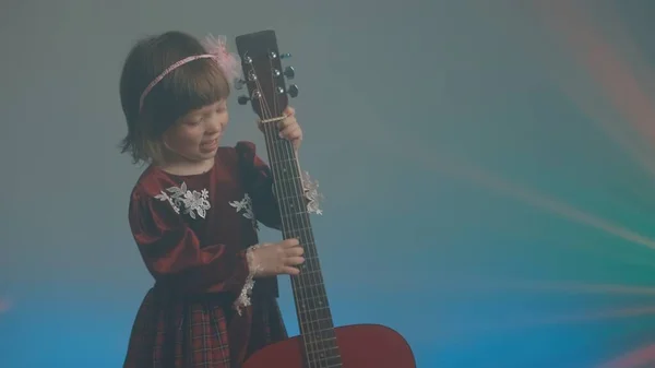 穿着老式衣服的小女孩弹奏的吉他听起来像双簧管 — 图库照片