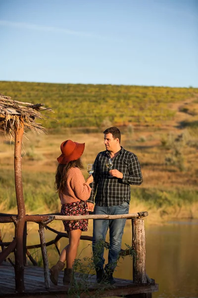 湖を背にした木製の池でワインを楽しむカップル — ストック写真