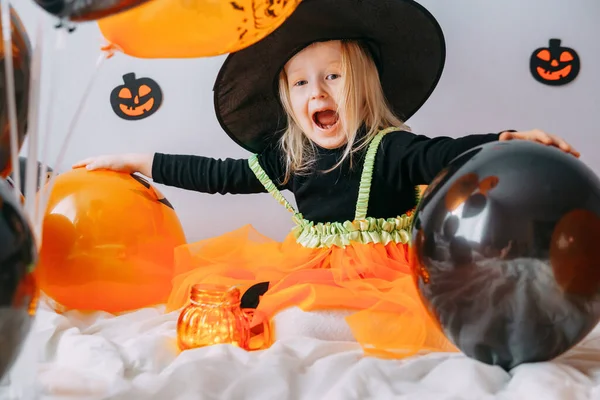 子供のハロウィーン 魔女の帽子の女の子と自宅で風通しの良いオレンジと黒の風船でカーニバルの衣装 ハロウィンを祝う準備ができて — ストック写真