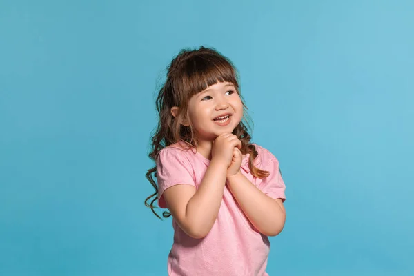 美丽的小女孩穿着粉红色的T恤是摆出一个蓝色的工作室背景 — 图库照片