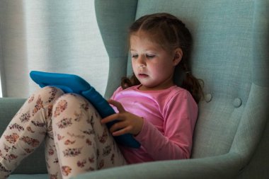 Küçük kız evde tablet bilgisayarla oynuyor. 