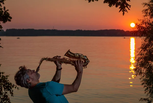 Adult Man Plays Saxophone Sunset River Evening — Stock fotografie