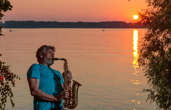 Adult Man Plays Saxophone Sunset River Evening — Stock fotografie