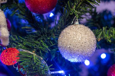 Noel ağacında parlayan beyaz top süsü yakın çekim gösterisi. Mavi ışıklarla izole edilmiş.