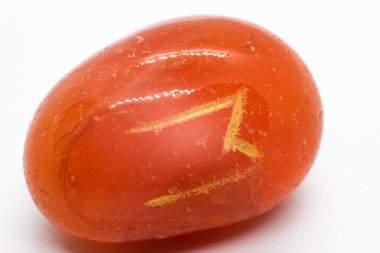 Ehwaz rune engraved into an opaque orange carnelian quartz tumbled and polished crystal. An orange polished mineral pebble isolated on white background surface   clipart