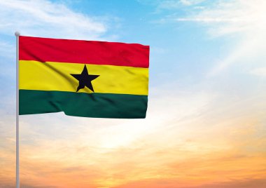 Bayrak direğine uzanan bir Gana bayrağının 3 boyutlu resmi ve arka planda gün batımlı güzel bir gökyüzü.