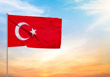 Bayrak direğine üç boyutlu bir Türkiye bayrağı konmuş ve arka planda gün batımlı güzel bir gökyüzü.