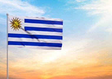 Uruguay bayrağının 3 boyutlu resmi bir bayrak direğine asıldı ve arka planda gün batımlı güzel bir gökyüzü