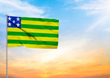 3D illustration of a Goias flag extended on a flagpole and in the background a beautiful sky with a sunset clipart