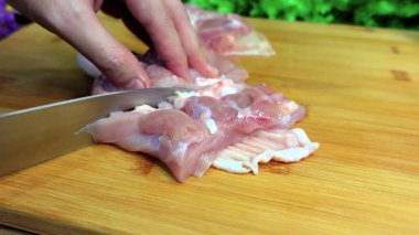 The cook cuts the chicken fillet on a wooden board