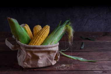  Koyu ahşap bir arka planda çuval içinde çiğ sarı mısır..