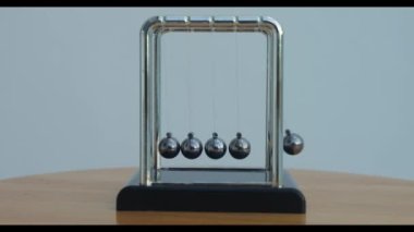 Newton toplarının yakın çekimleri, sallanan metal kürelerle, pencere eşiğinde, tropikal doğa arka planına karşı.