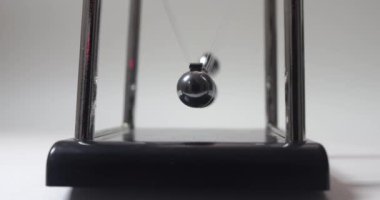 Yakın plan. Kromatik küreleri sallanan ve yavaşlayan Newton toplarının ön görüntüsü. Kinetik sarkacı. Hareket. Eylemsizlik