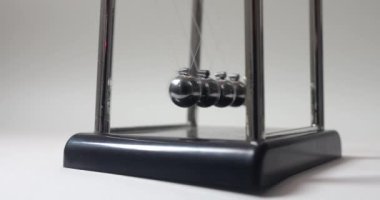 Newtons beşiğini beyaz bir arkaplan üzerinden hareket ettirmeye yakın çekim. Sonsuz döngü. Kinetik sarkacı