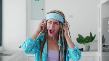 Afro saçlı hippi kadın kulaklık takıyor, ağır müzik dinliyor, kulaklığın ses kalitesi konusunda heyecanlı.
