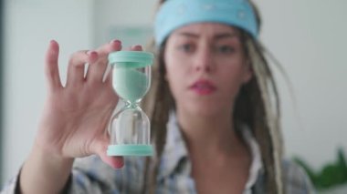 Genç bir hippi kadının ellerinde akan kum saatleri, kumun baskı altında nasıl aktığını gösteriyor. Süre