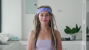 Rasta bukleli neşeli genç bir kadının yakın plan portresi modern iç mekanda kameraya bakıp gülümsüyor. İnsanlar ve tarz kavramı.