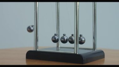 Bir Newtons beşiğini hareket ettiren bir elin yakın çekimi. Kinetik sarkacı. Metal toplar sallanır ve yavaşlar. Bir şeyleri taşımak, eylemsizlik konsepti, bilim, fizik dersi. Psikolojik hipnoz seansı
