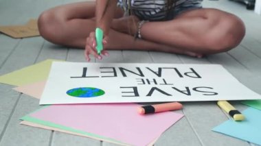 Gezegeni kurtarmak için kadın eli posterleri çizerken yavaş çekimde. Çerçeve omuz üstünde