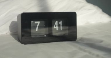 Modern dijital çalar saat sabah 7: 41 'de beyaz arka plana düşen güneş ışığıyla birlikte yatak odasında çalıyor. Alarm saati 8 'e ayarlandı. Uyanma ve işe gitme zamanı. Sabah Kavramı