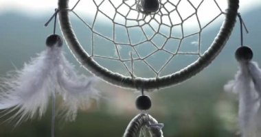 Tüyleri, iplikleri ve boncukları tropikal arka planda asılı olan bir düş kapanı görüntüsü..