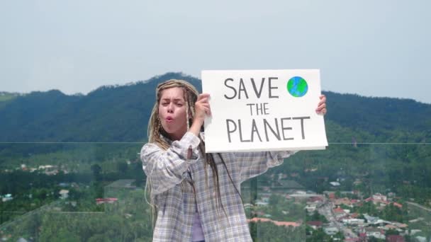 年轻女性生态活动家的肖像 带着恐惧的头发 站在自然的背景上看着相机 拿着地球模型旗帜拯救我们的地球的严肃的千年妇女 — 图库视频影像