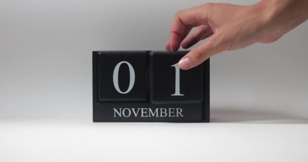 秋天的一个月 十一月 一只男人的手把黑色的木制立方日历翻过来 靠着白色的背滴 — 图库视频影像