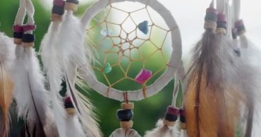 Tüyleri, iplikleri ve boncukları tropikal arka planda asılı olan bir düş kapanı görüntüsü..