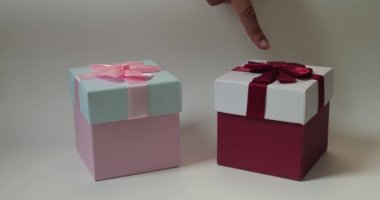 İki hediye kutusuna yakın plan ve sonra pembe kutuları seçerek kırmızıyı işaret eden parmak ucu. Boks Günü