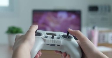 Arka planda televizyonla elinde video klavye oyunu oynayan genç bir kızın görüntüsü