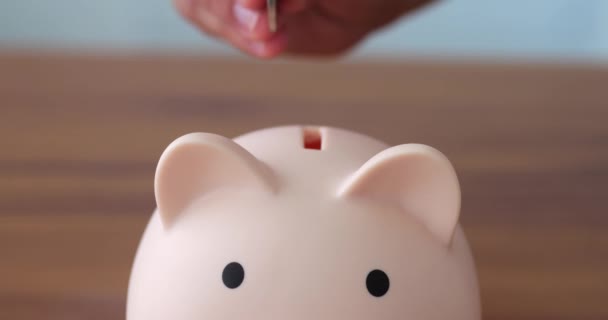 Mans Hand Legt Münzen Sparschwein Schweineform Auf Weißem Hintergrund — Stockvideo