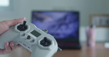 Uçuş simülatörü konsepti. Kadın eller bulanık bir monitörün arka planında FPV drone 'dan joystick' i tutar..