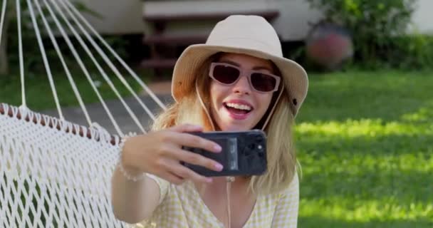 Atrakcyjna Młoda Blondynka Siedzi Hamaku Robi Selfie Aby Podzielić Się — Wideo stockowe
