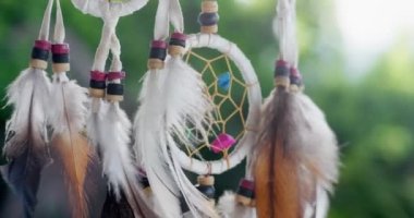 Tüyleri, iplikleri ve boncukları tropikal arka planda asılı olan bir düş kapanı görüntüsü..
