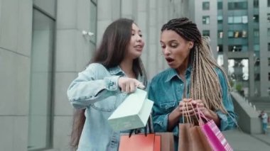 Two female friends stand on street near business districts boast their new acquisitions in packages Two emotional female boast about who has better things Concept of boast or competition who is better