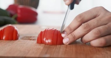Vejetaryen kadın elleri mutfakta domatesleri ince dilimlere ayırıyor. Yakın çekim elleri, salata için tahtada kırmızı domates kesiyor. Kahvaltıda sağlıklı vejetaryen yemeği. sağlıklı beslenme vegan gıda konsepti